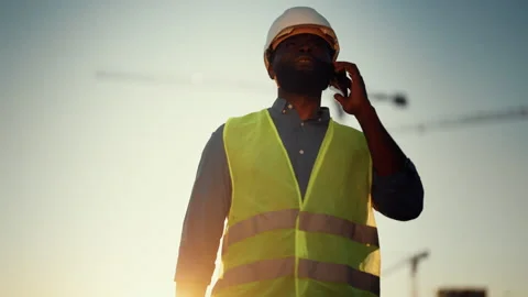 Chief engineer talking by mobile phone, portrait of african man at building area Stock Footage 318710279