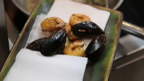 Chief hand puts fried shrimp and other seafood into a plate Stock Footage 123802542