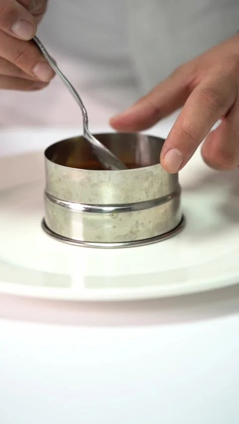 Chief plating a gourmet dish with vegetables and meat in a minimalist style Stockbeeldmateriaal 334840455