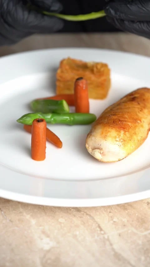 Chief plating roasted chicken piece with carrots and green beans on a plate 스톡 동영상 328964360