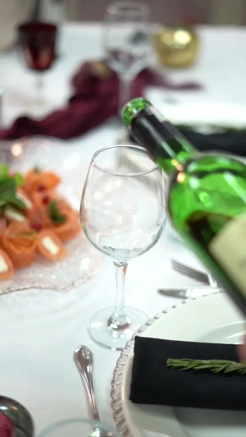 A chief pours green wine bottle on an empty wine glass on a decorated dinner Stock Footage 331201137