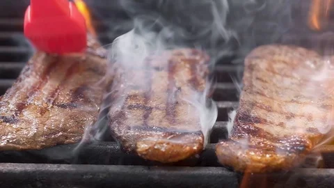 The chief puts a red silicone brush olive oil on steaks. Slow motion, close-up. Stock Footage 107906976