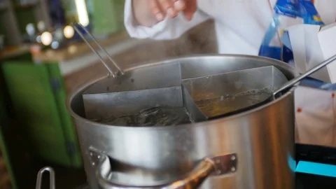 Chief puts spaghetti into boiling water. Close up of cooking macaroni. Macaroni 스톡 동영상 75393713