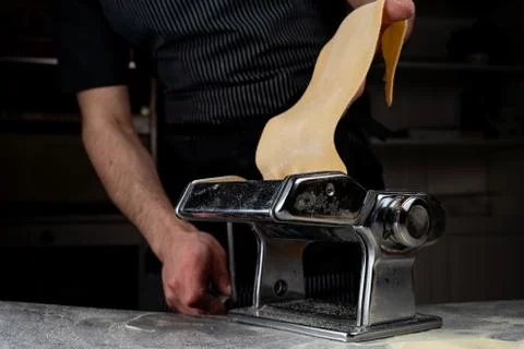 Chief is rolling raw dough in a spaghetti machine to make homemade spaghetti, Stock Photos