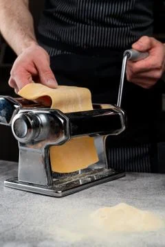 Chief is rolling raw dough in a spaghetti machine to make homemade spaghetti, Stock Photos