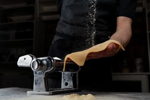 Chief is rolling raw dough in a spaghetti machine to make homemade spaghetti, Stock Photos