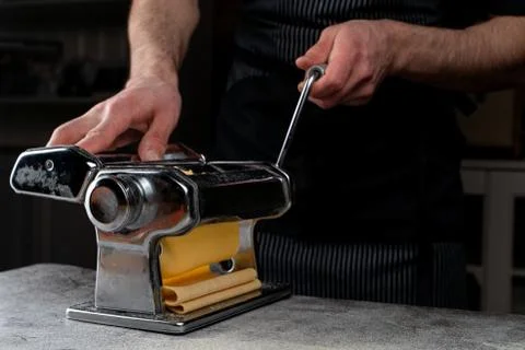 Chief is rolling raw dough in a spaghetti machine to make homemade spaghetti, Stock Photos
