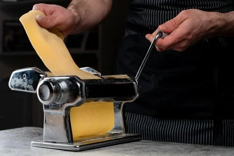 Chief is rolling raw dough in a spaghetti machine to make homemade spaghetti, Stock Photos