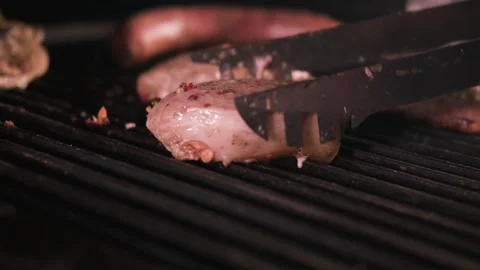 Chief using the tong and turning the meat on the grill. close up slow motion. Stock Footage 130786882