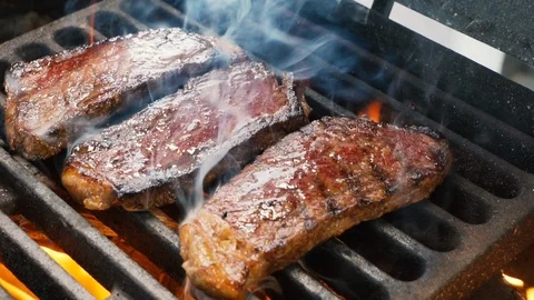 Chief using the tongs and turning the meat on the grill Stockbeeldmateriaal 108351611