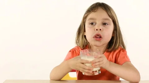 Child 4-5 years old, girl. She drinks milk from a glass beaker, gets up and l Stock Footage 83814543