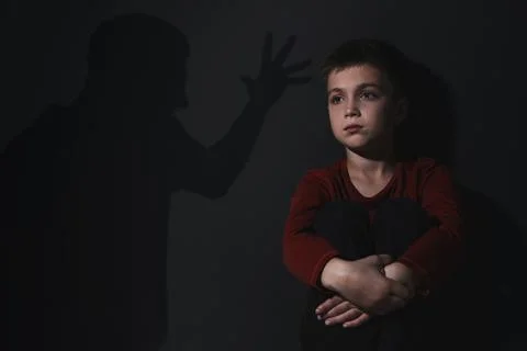 Child abuse. Father threatening his son. Shadow of man on wall Stock Photos