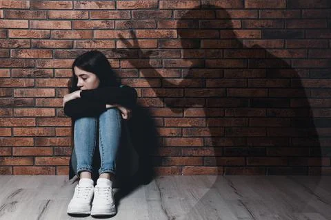 Child abuse. Father yelling at his daughter. Shadow of man on brick wall Stock Photos