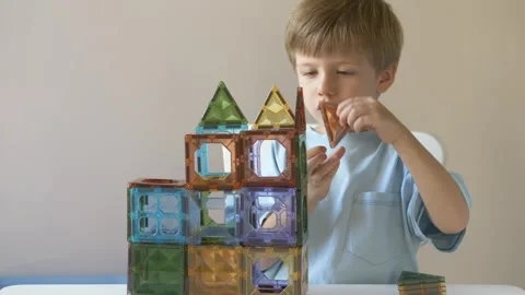 Child is actively constructing a vibrant structure using magnetic tiles Stock Footage 318294159