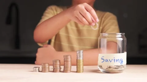 Child Adding Coins to Savings Jar Stock Footage 294700153