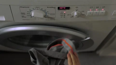 A child adds laundry to the washing machine Stock Footage 322682014