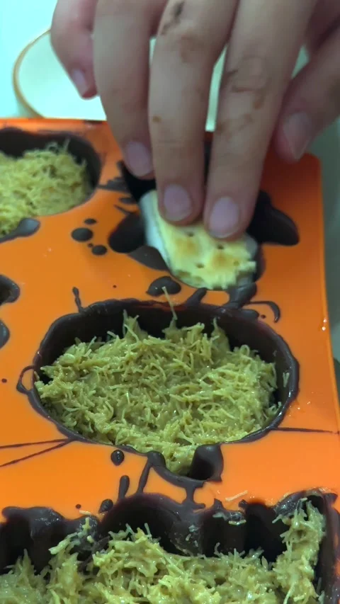 Child adds marshmallow and cracker to chocolate mold, mixing textures with Video stock 343478283