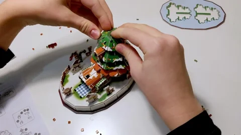 A child adds a small candy cane decoration to a Christmas craft. The step b.. Stockbeeldmateriaal 316595630