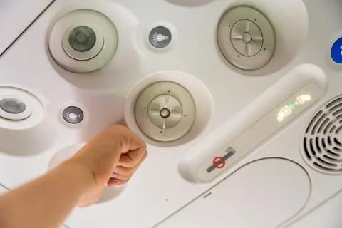 Child adjusting the overhead panel on an airplane Stock Photos