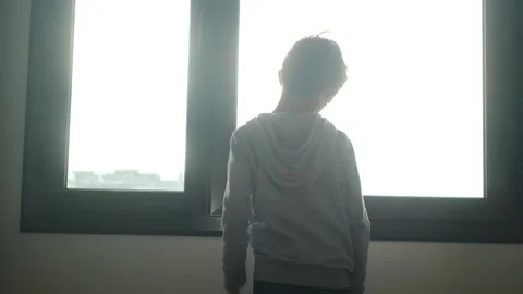 Child alone in front of a large window with his back to himself. Stockbeeldmateriaal 270461391