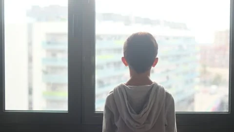 Child alone in front of a large window with his back to himself. Video stock 270461431
