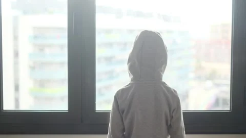 Child alone in front of a large window with his back to himself. Video stock 270461438