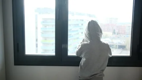 Child alone in front of a large window with his back to himself. Video stock 270461473