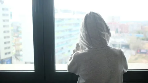 Child alone in front of a large window with his back to himself. Video stock 270461476