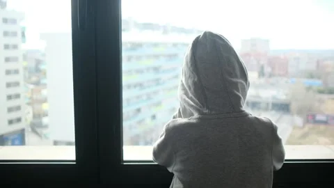 Child alone in front of a large window with his back to himself. Video stock 270461483