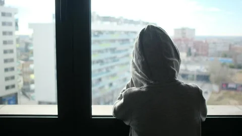 Child alone in front of a large window with his back to himself. Video stock 270461488