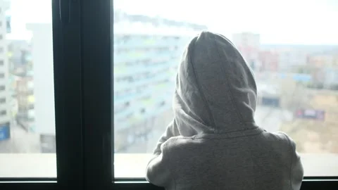 Child alone in front of a large window with his back to himself. Video stock 270461490