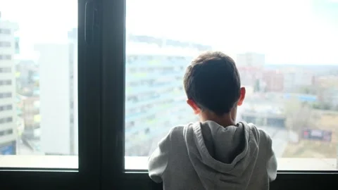 Child alone in front of a large window with his back to himself. Video stock 270461507