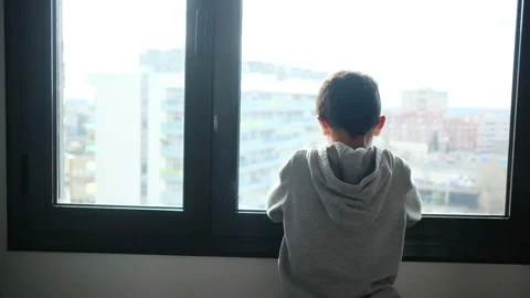 Child alone in front of a large window with his back to himself. Video stock 270461519