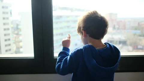 Child alone in front of a large window with his back to himself. Video stock 270461566