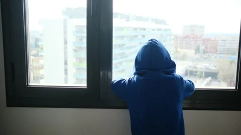 Child alone in front of a large window with his back to himself. Vídeos de archivo 270461616