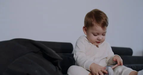 A child alone at home on the couch, playing with his mobile phone. Slow motion. Stock Footage 149070998