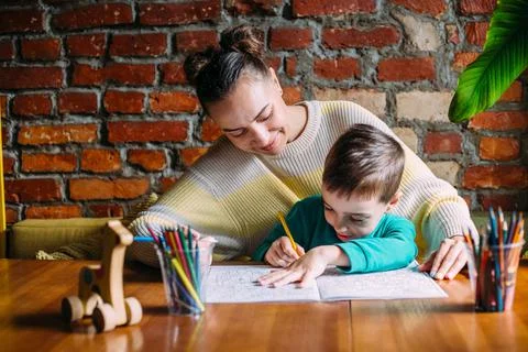 Child and adult are drawing a coloring book. Stock Photos