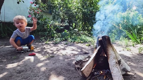 Child and fire with smoke. Rest in the village. Bonfire, baby burns, danger Stock Footage 209341306