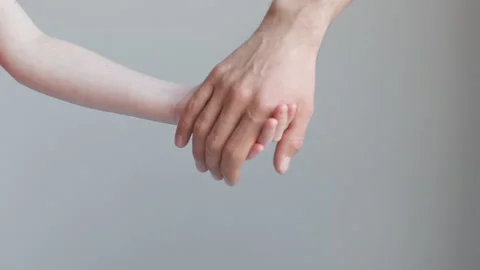 Child and man join hands and hold against the background of a white wall Stock Footage 170546194