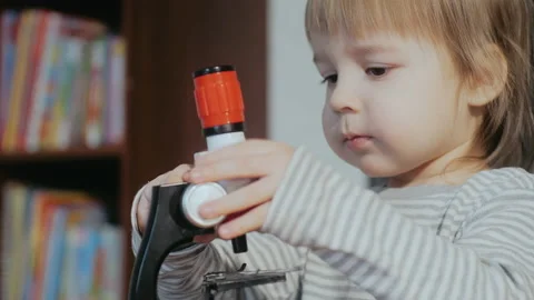 Child and a microscope. Toddler playing with a child's developing toy. Cognitive Stock Footage 151695512