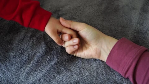 Child and mother hands in red clothes on bed gray background, family Stock Footage 240863853