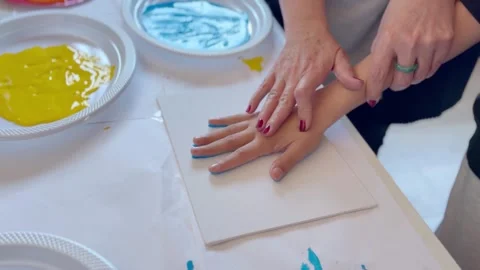 Child and teacher make handprint painting as a Mother’s Day gift Stock Footage 333010132