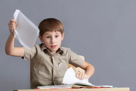 The child is angry at homework. An elementary school student is tearing paper. Foto stock
