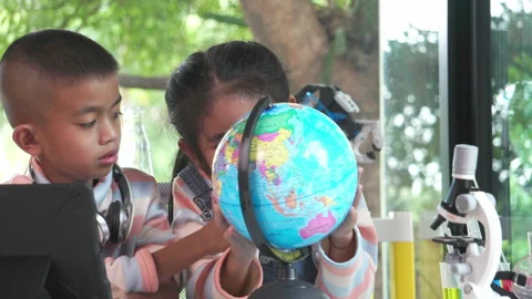 Child asia inspecting a model of the earth with a magnifying glass at home Stock Footage 247498341
