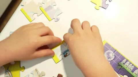 Child assembles puzzles on a white table. Close-up Stock Footage 317918370