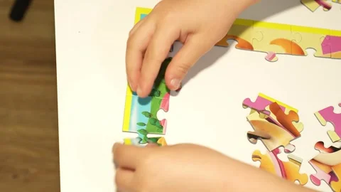 Child assembles puzzles on a white table. Close-up Stock Footage 317918461