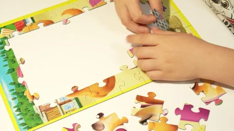 Child assembles puzzles on a white table. Close-up Stock Footage 317918468