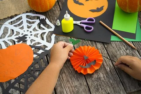 Child assembling DIY Halloween decorations with scissors and glue stick out.. Stock Photos