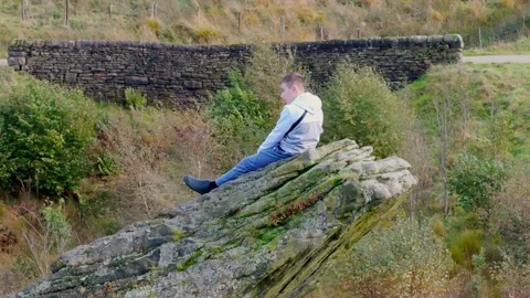 Child atop a substantial boulder, immersed in contemplation. Aerial footage.. Stockbeeldmateriaal 254161141