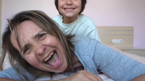 Child from back attacks his resting on bed mother Stock Footage 131358678